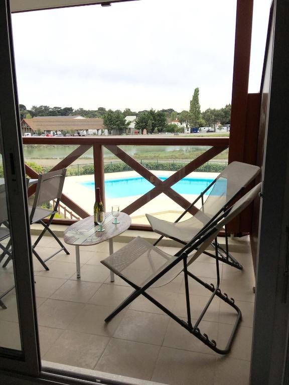 a balcony with a table and chairs and a view of a pool at Appartement cosy avec piscine partagée - Guérande - 30 m² in Guérande