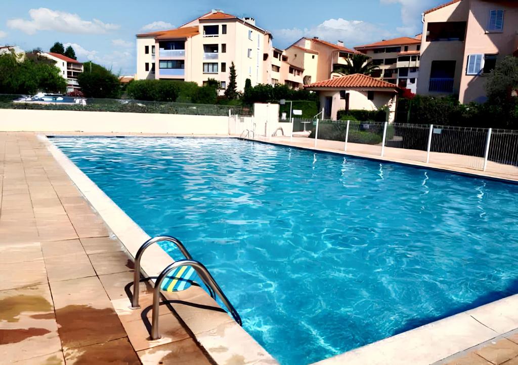a swimming pool with a chair in front of a building at Studio charmant à Fréjus avec piscine commune - 30 m² in Fréjus