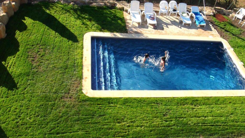 two people swimming in a swimming pool with lawn chairs at Charming Villa in Llobera with Private Pool in Llanera