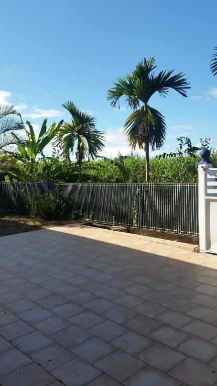 a fence with palm trees in the background at Appartement confortable avec terrasse à Petit-Canal - 50 m² in Petit-Canal