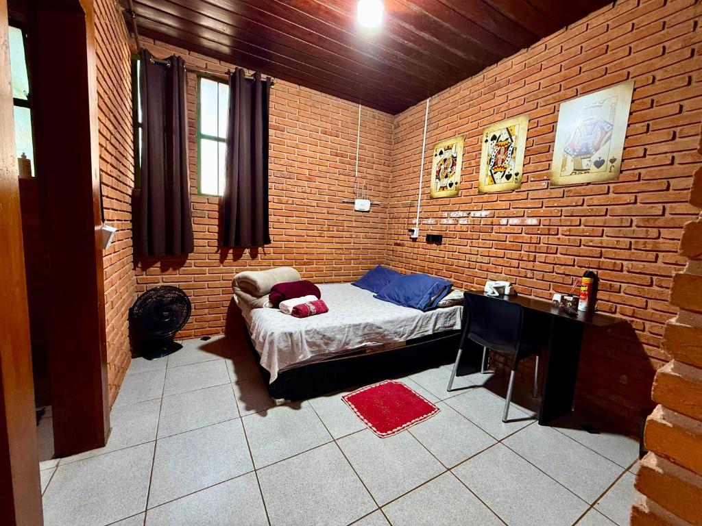 a room with a bed and a brick wall at Quarto com Banheiro Privado no Centro de Botucatu in Botucatu