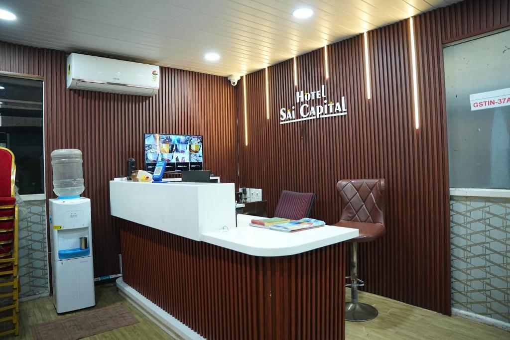 a lobby with a white counter and a chair at Hotel Sai Capital in Vijayawāda