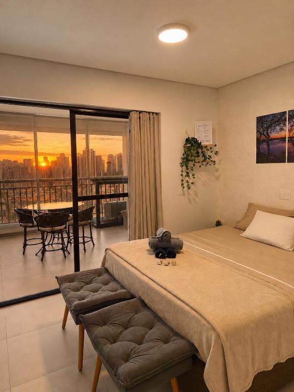 a bedroom with a bed and a view of the city at Studio Pôr do Sol - Garagem - Piscina - Anhembi in São Paulo