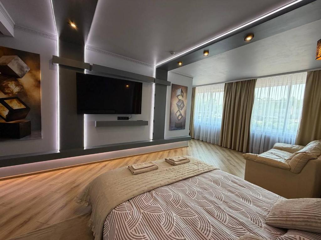 a bedroom with a large bed and a flat screen tv at ADAM Apartments Krāslava in Krāslava