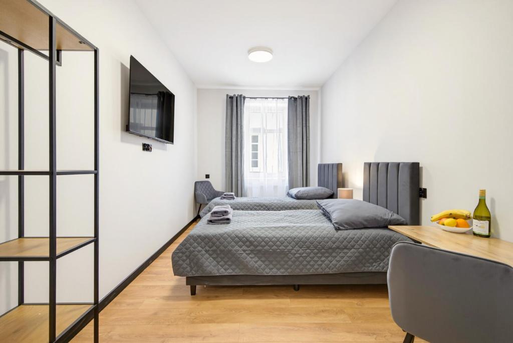 a bedroom with a bed and a table and a television at Centrum Grand Apartments in Rybnik