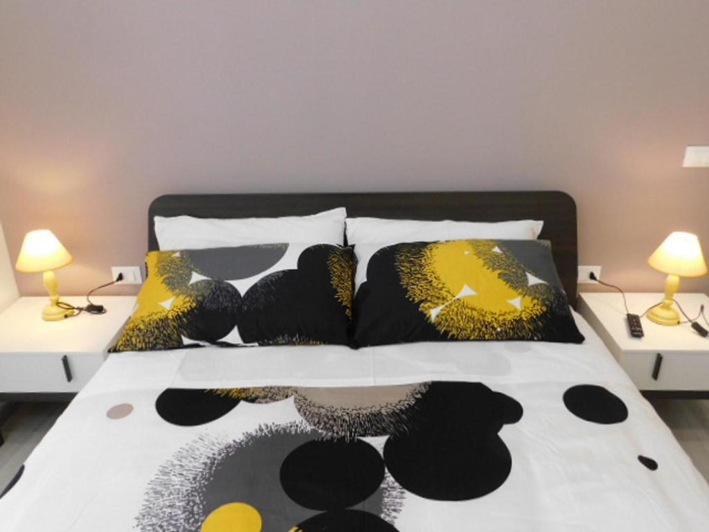 a bed with black and yellow pillows and two lamps at Contemporary Apartment in Trapani, 50 m² with Balcony in Trapani