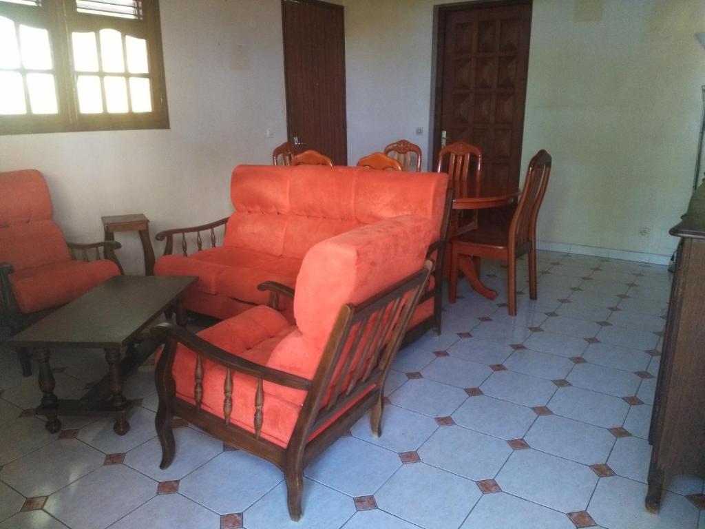 a living room with orange chairs and a table at Appartement panoramique Bouillante in Bouillante
