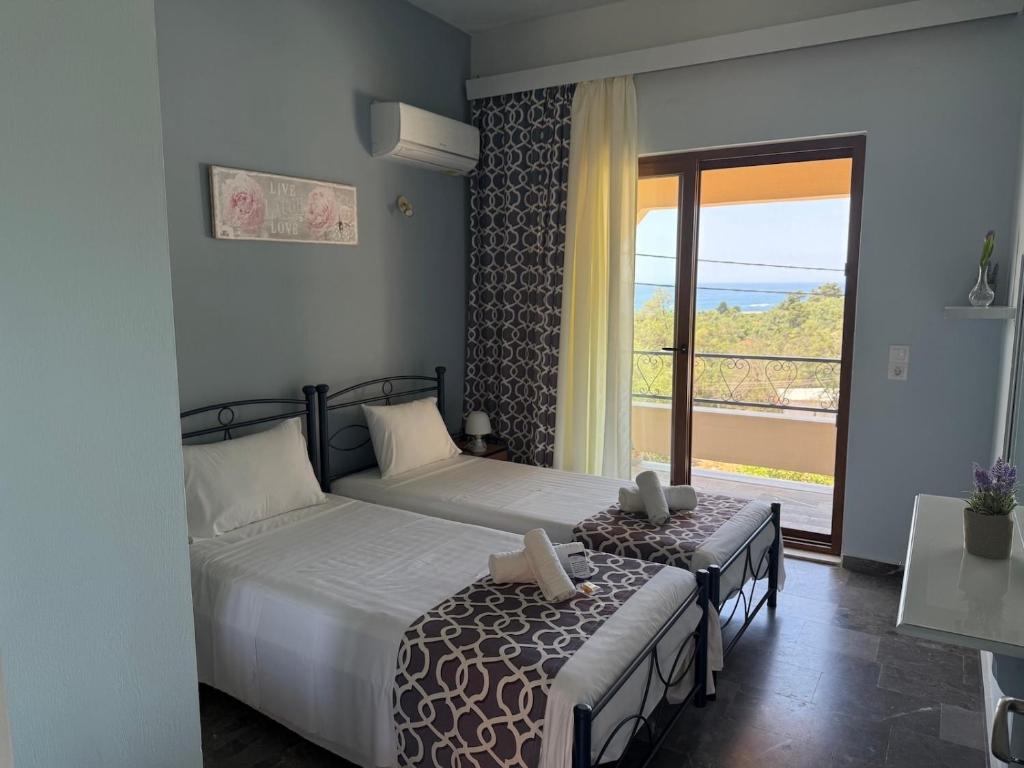 a bedroom with two beds and a balcony at Loukia's apartment no 2 in Mesochórion