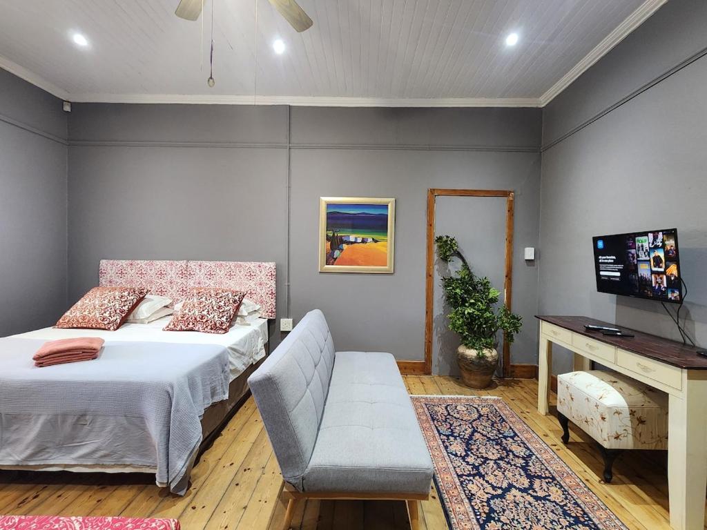 a bedroom with a bed and a desk and a television at GreenMarket Apartment in Knysna