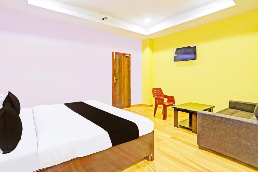 a bedroom with a bed and a couch and a table at Hotel O Nandhi Inn in Vemalwāda