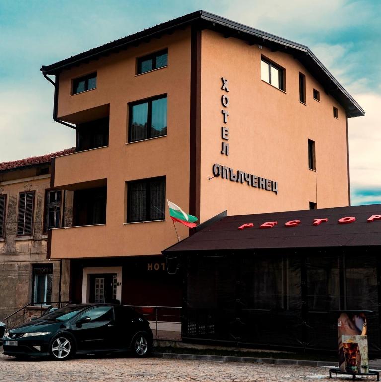 a black car parked in front of a building at Hotel Opalchenets Стаи за гости и парти зала in Shipka