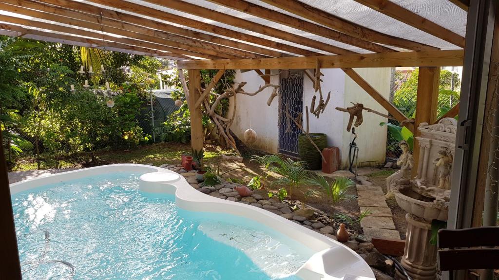 a hot tub in a backyard with a pergola at Appartement moderne à Le Lamentin avec piscine partagée - 20m² in Le Lamentin