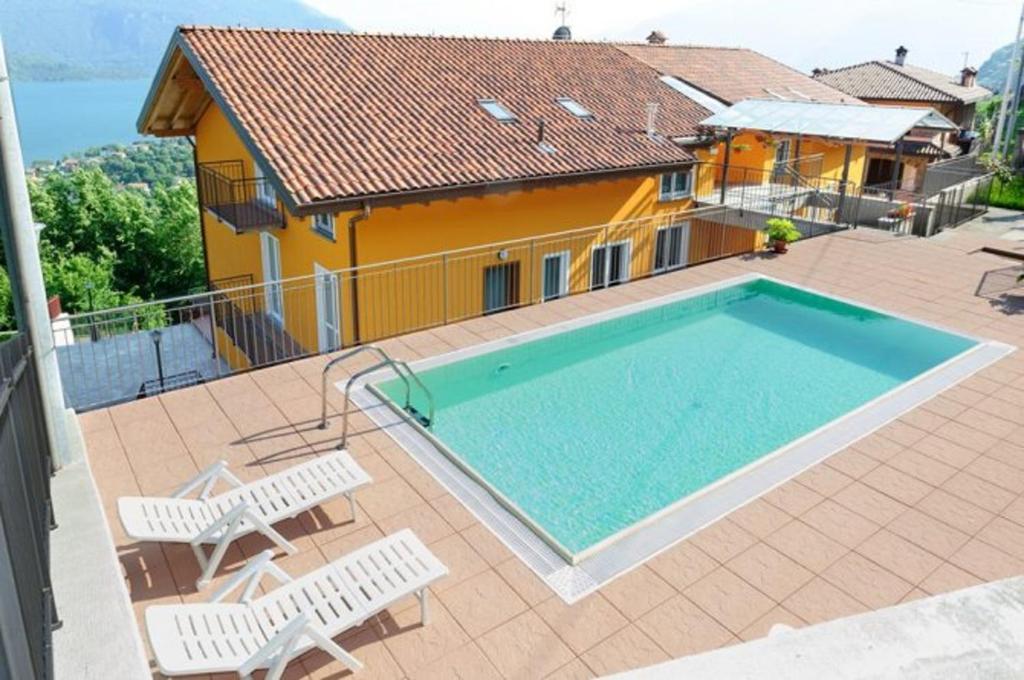 a swimming pool with two chairs and a house at Lake View Apartment in Vercana, Shared Pool in Vercana