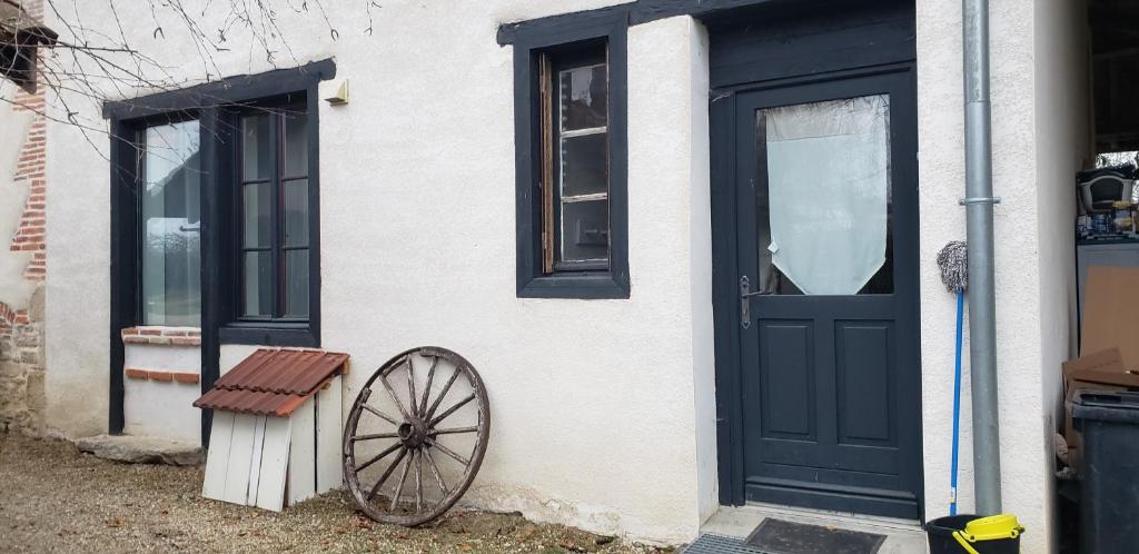 a house with a black door and a wooden wheel at Studio - Le Saule in Foissiat