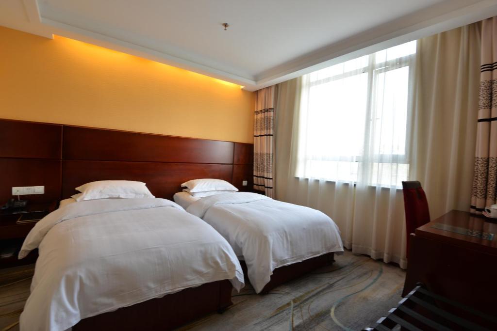 two beds in a hotel room with a window at Irene Boutique Hotel - Jinshu Shop in Shanghai