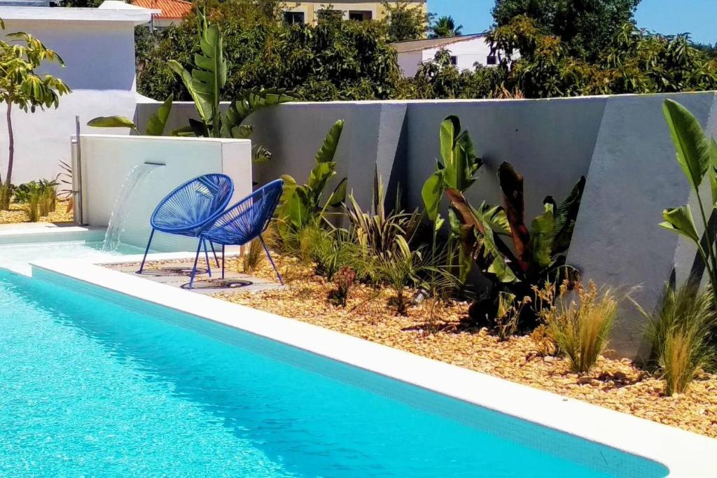 a pool with two chairs next to a fence at Modern apartment in Estói with shared pool. in Estói