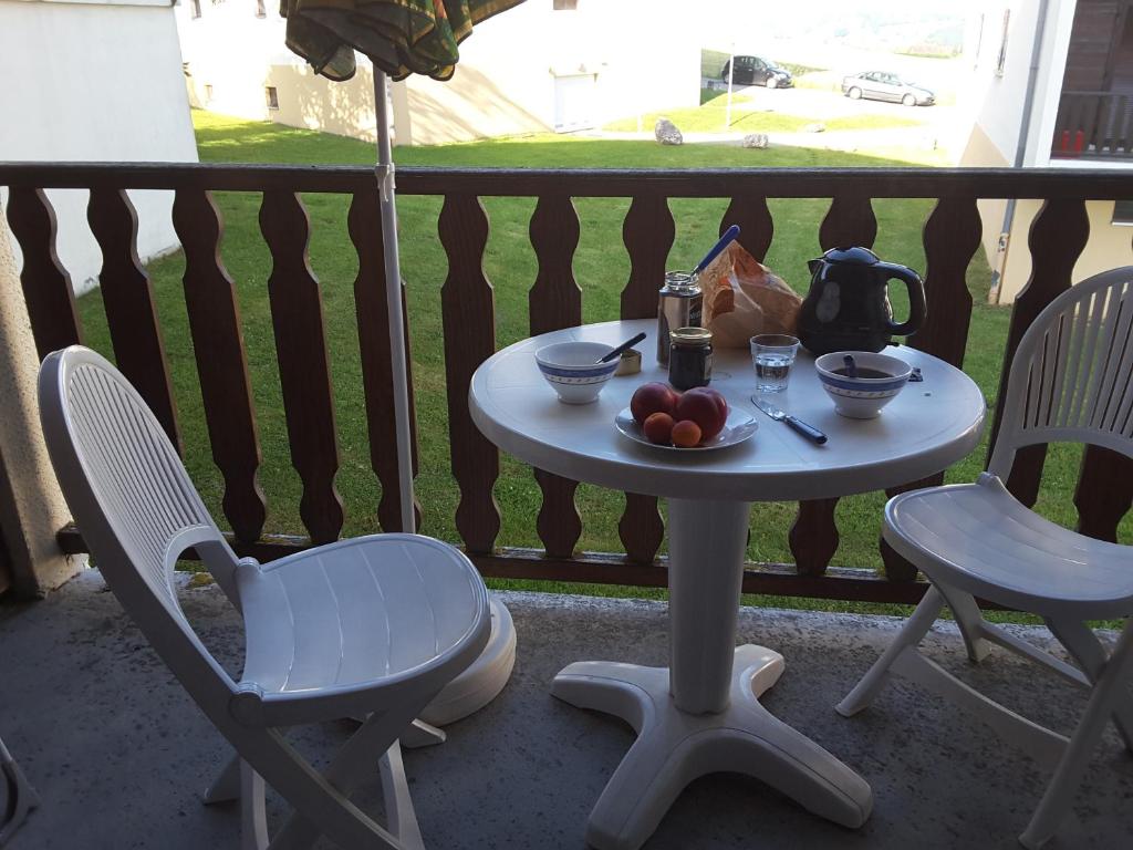 a table and chairs on a porch with a bowl of fruit at Appartement cosy avec piscine privée à Métabief - 38 m² in Métabief