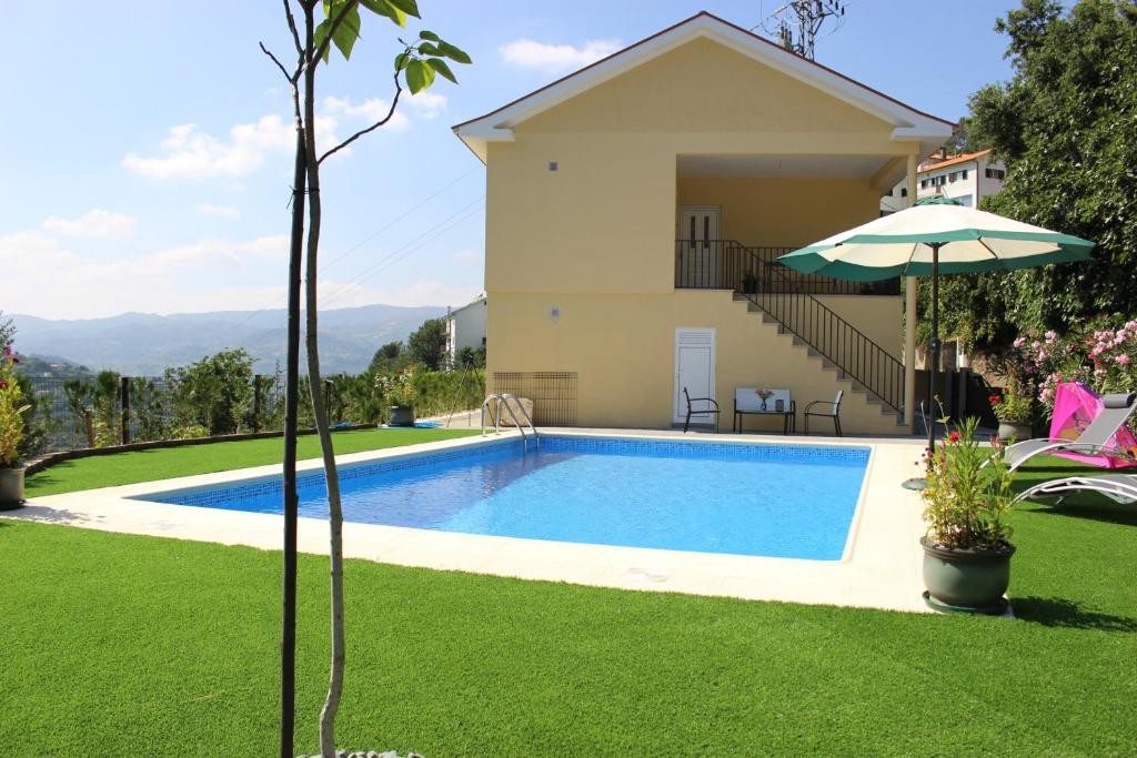 a swimming pool in front of a house with an umbrella at Peaceful villa in São Martinho de Mouros with private pool in Frende