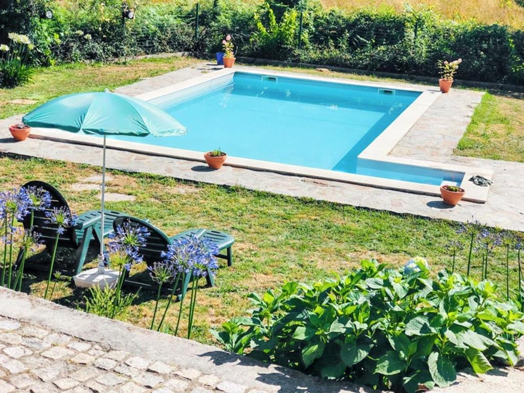 a swimming pool in a yard with two chairs and an umbrella at Cozy house in Águeda 45 m² with shared pool in Urgueira