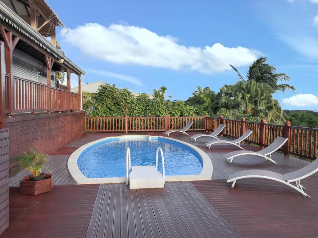 a swimming pool on a deck with chairs around it at Villa de charme à Sainte-Anne avec piscine privée in Sainte-Anne