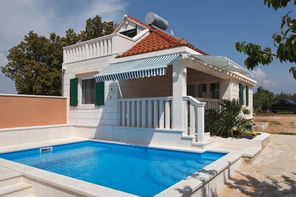 a villa with a swimming pool in front of a house at Charming Villa in Pučišća + Pool in Pučišća