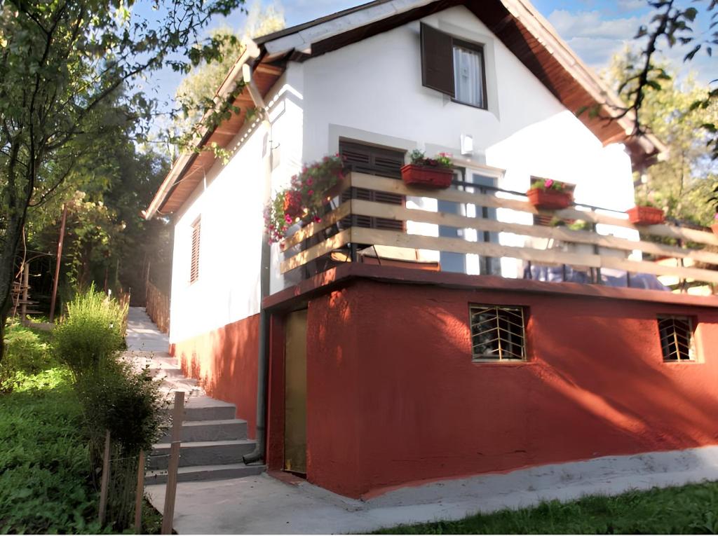 a red and white house with flowers on the balcony at Cozy House in Jazvine with Garden in Jazvine