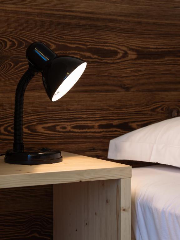 a black lamp sitting on a table next to a bed at Hotel Hello in Monguelfo