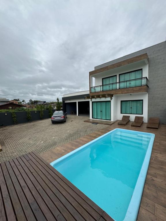 a large blue swimming pool in front of a house at Casa Completa em Picarras, Piscina, Sinuca e Churrasqueira in Piçarras