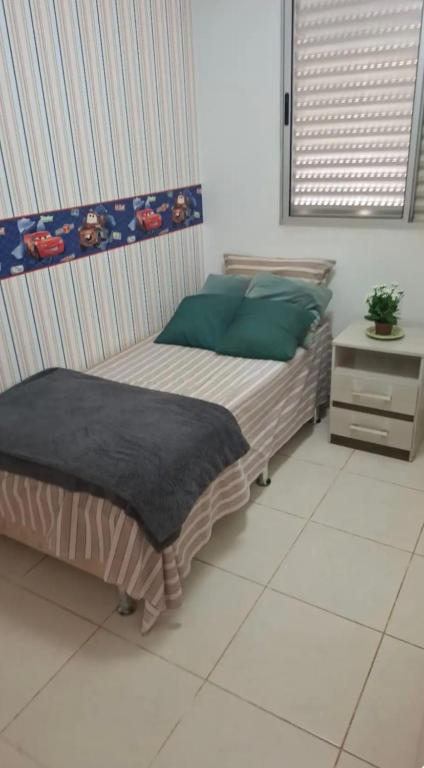 a bedroom with a bed with green pillows and a table at Lindo quarto centro Uberlândia in Uberlândia