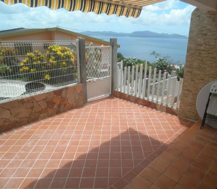 a patio with a fence and a view of the water at Appartement moderne à Schoelcher avec terrasse et vue mer in Schœlcher