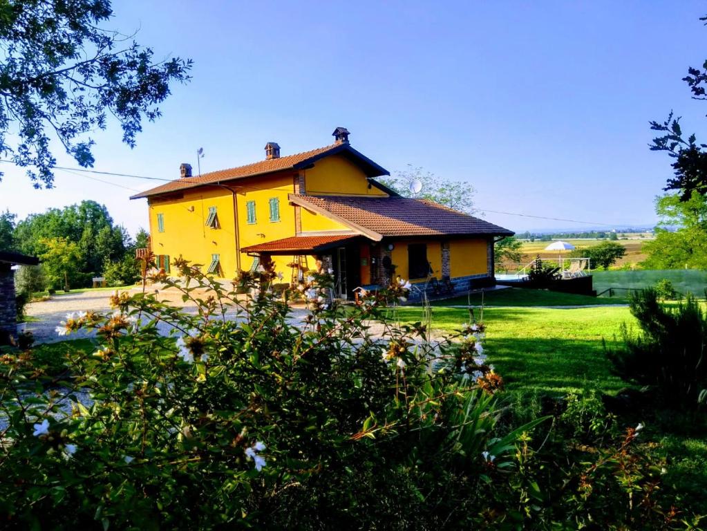 a yellow house sitting on top of a lush green yard at Cascina Rocchino bed and breakfast in Predosa