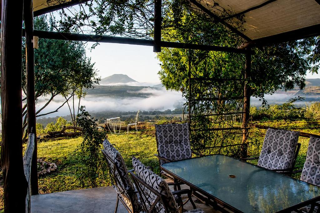 a table and chairs on a porch with a view of a mountain at OPPIBERG GUEST HOUSE and SPA in Hartbeespoort