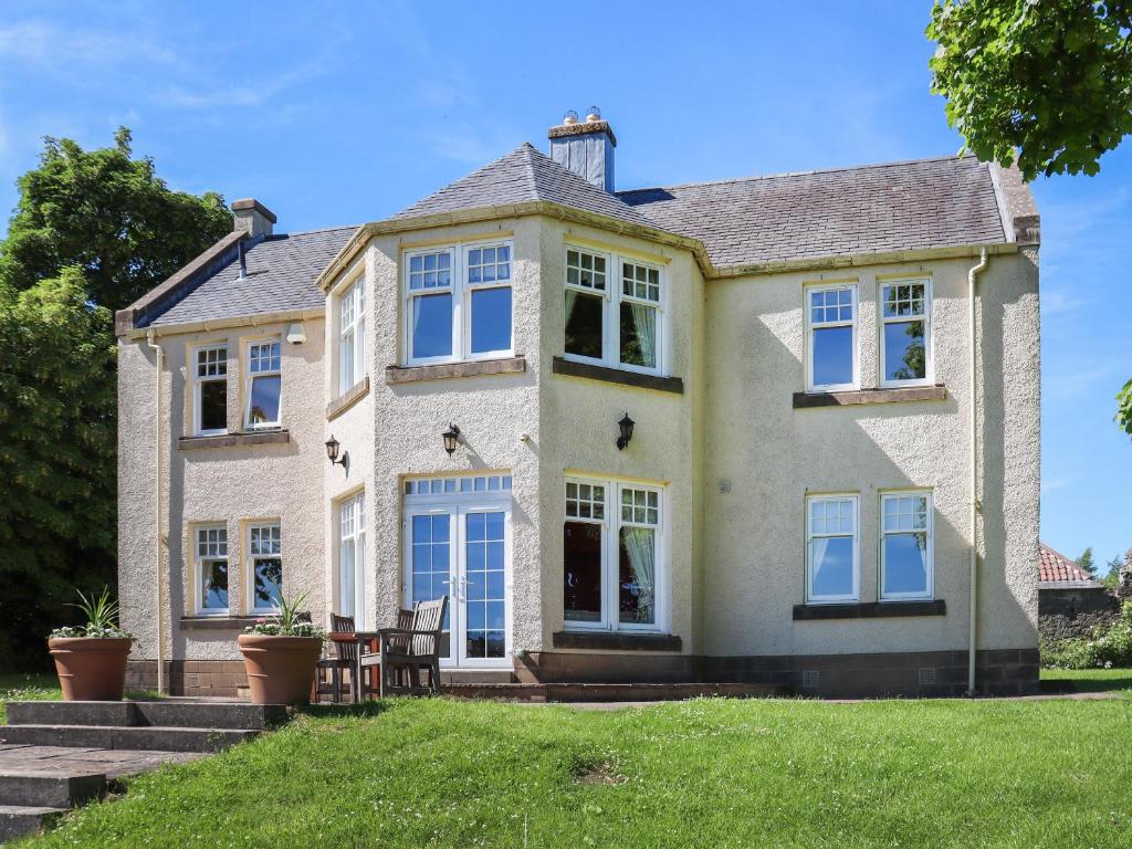 a large house with blue windows on a lawn at Hall Teasses Lodge - Uk52175 in Leven