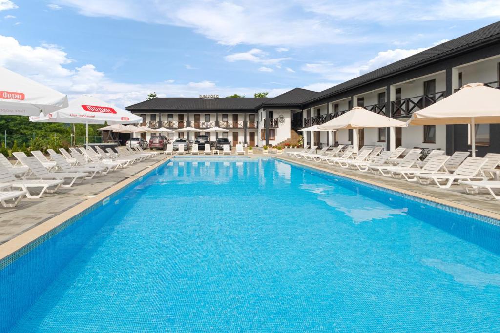 a large swimming pool with white chairs and a hotel at ROMANTIK in Solotvyno