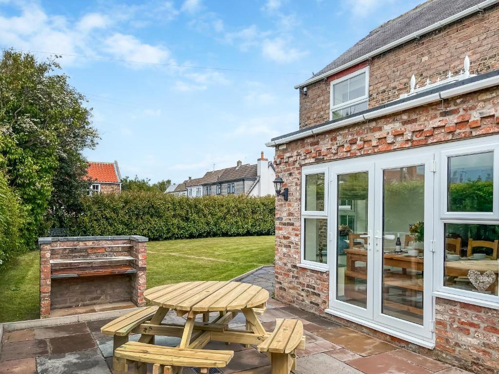 a patio with a wooden table and a picnic bench at Old Master's Cottage in Leven