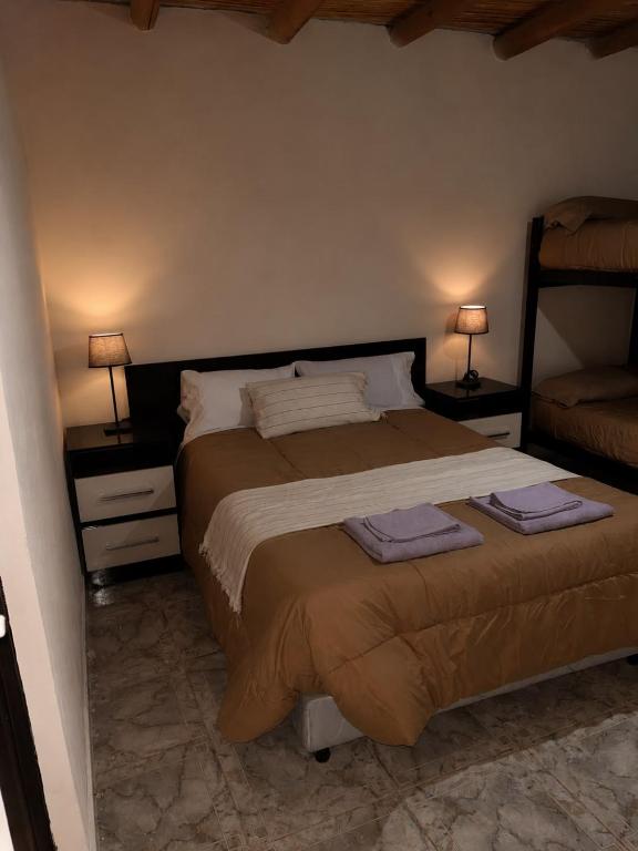 a bedroom with a large bed with two lamps on the sides at Talahuasto in Los Baldecitos