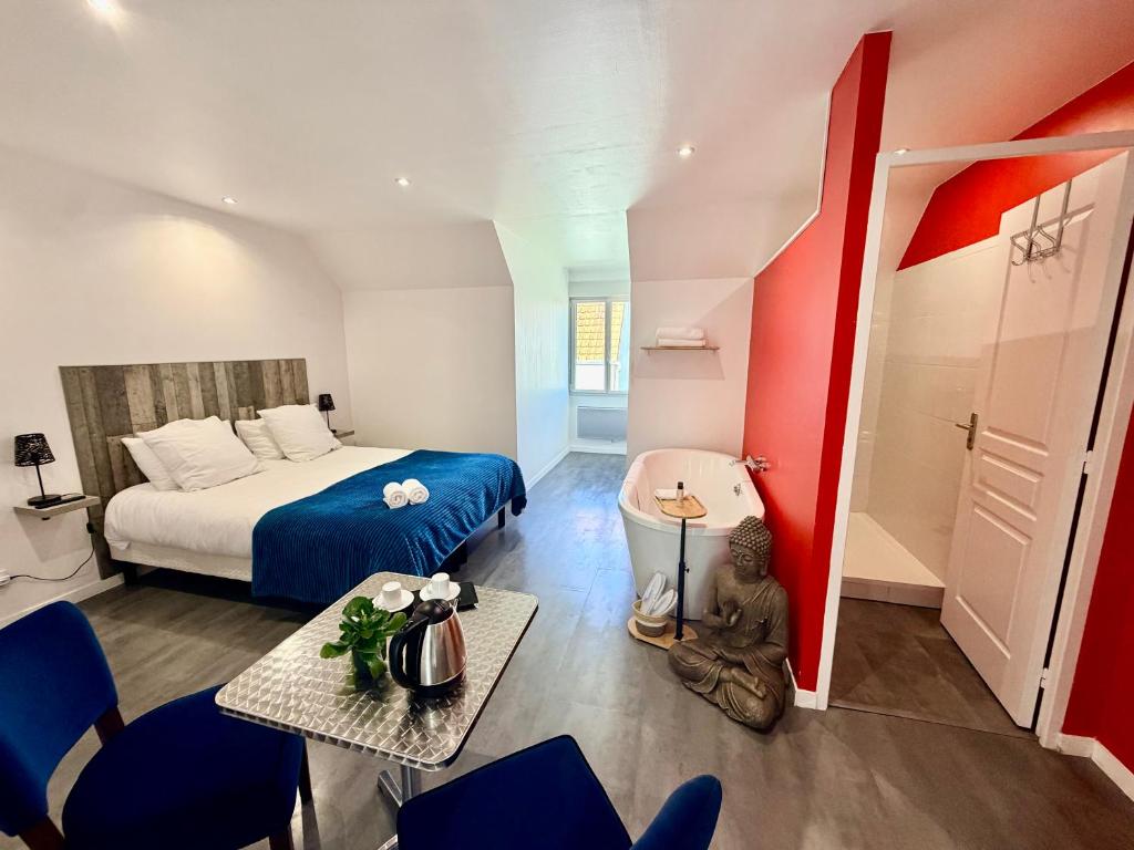 a small room with a bed and a table and chairs at Aux Charmes - Suites Prestige et Petit Déjeuner en chambre - Cote d Opale in Isques