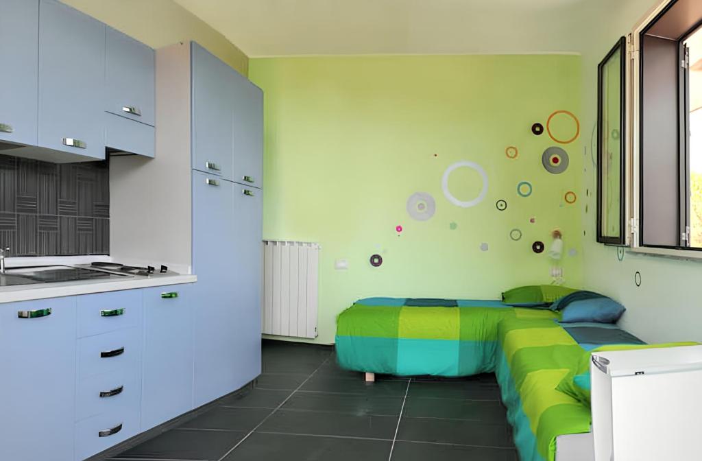 a bedroom with a green bed and a kitchen at Comfortable Studio in Nicolosi, 25 m² in Nicolosi