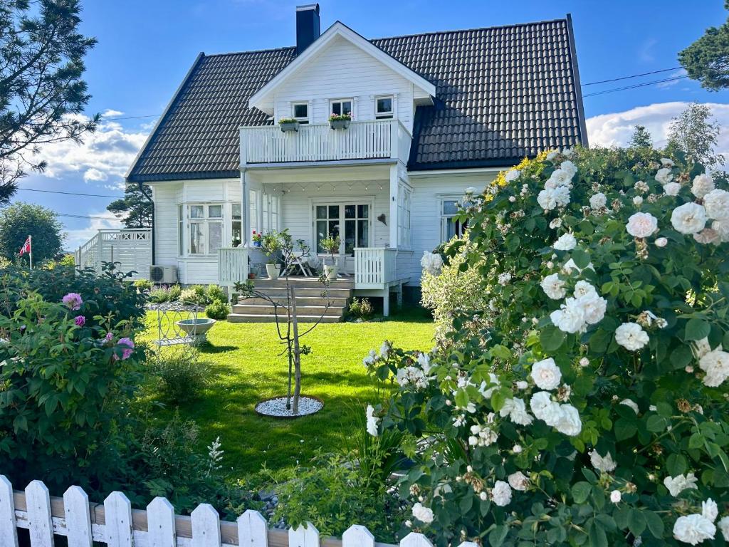ein weißes Haus mit weißem Zaun und Blumen in der Unterkunft Lenes hus in Halden