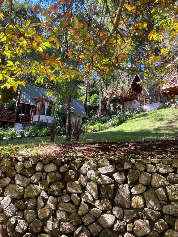 a stone wall in front of a house at VELINN Pousada Canto da Cascata in Camanducaia