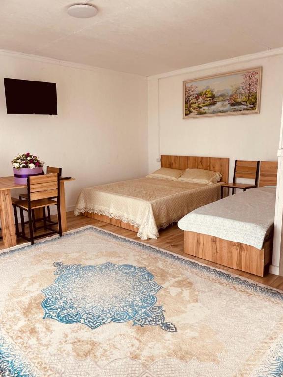 a bedroom with two beds and a desk with a television at Гостевой дом Бакай in Imeni Kirova