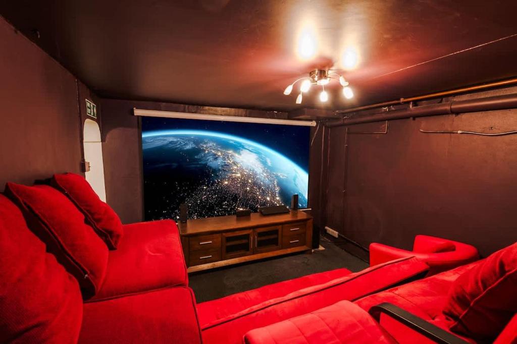 a cinema room with red chairs and a large screen at Ascot House in Buxton