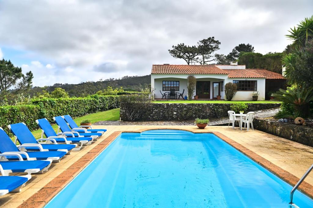a pool with chairs and a house in the background at Casa do Moinho in Ulgueira