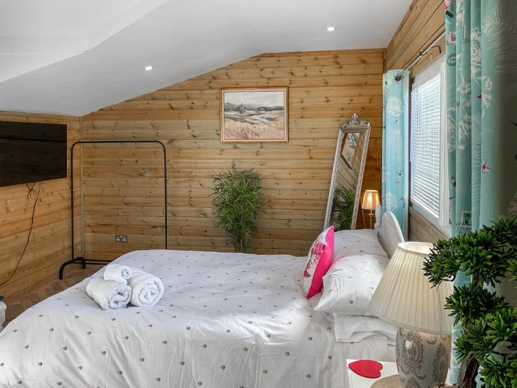 a bedroom with a bed in a room with wooden walls at Eagle Lodge in Cowbridge