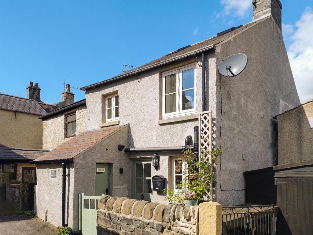 a gray house with a window and a fence at Fern Cottage in Bradwell