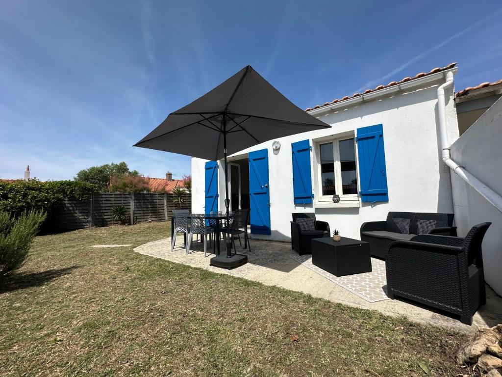 a patio with a table and an umbrella at L'Epine Bleue in LʼÉpine