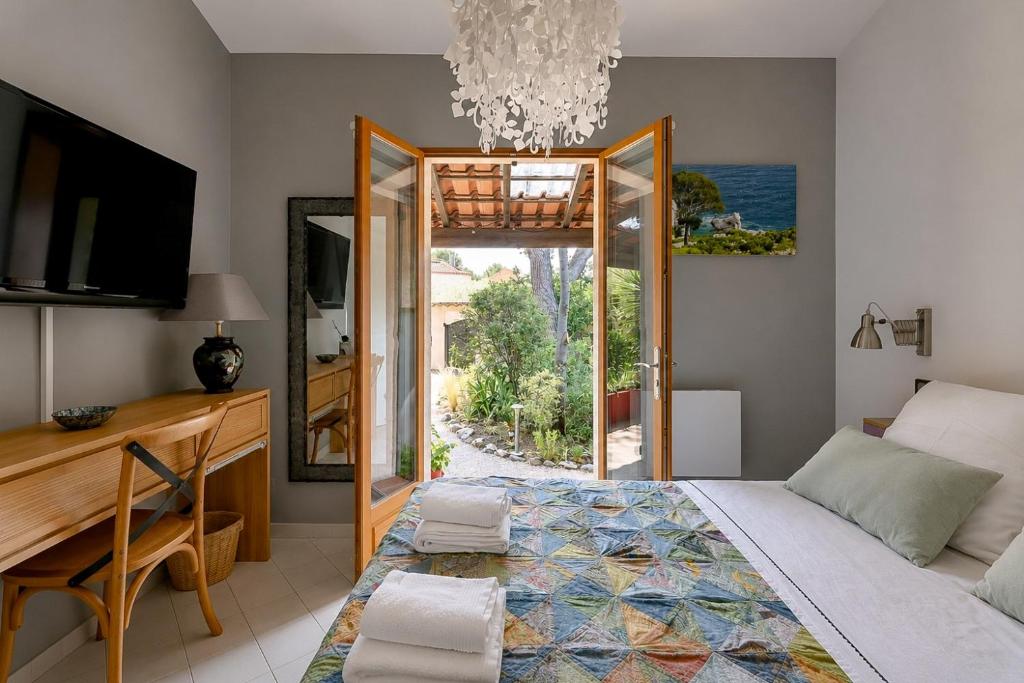 a bedroom with a bed and a desk and a window at Cap Anguilla, chambre d'hôtes in Carnoux