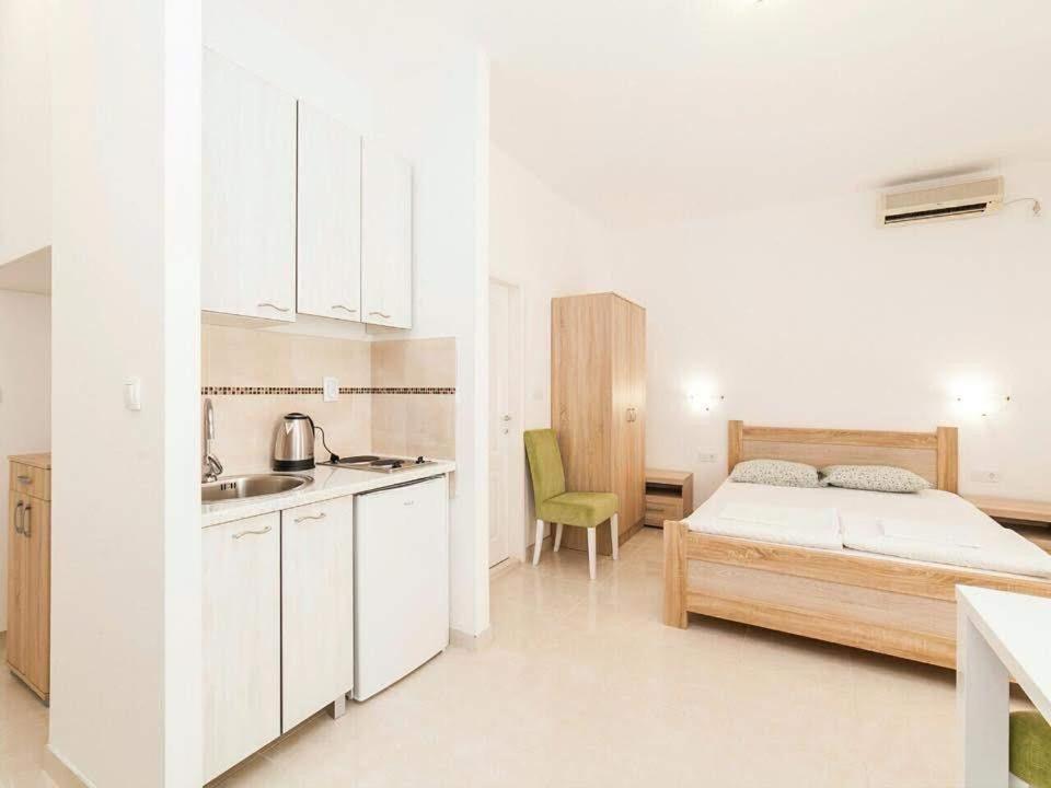 a white bedroom with a bed and a kitchen at Studio Apartment in Kaluđerac