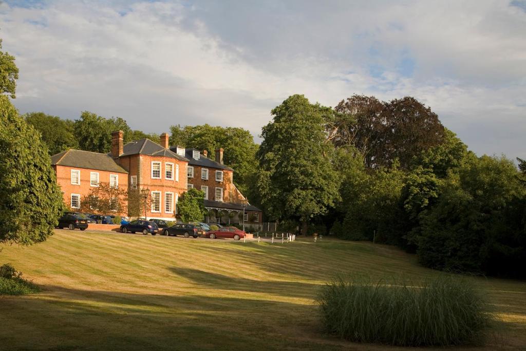 a large brick house with cars parked in a field at Brandshatch Place Hotel & Spa in Dartford