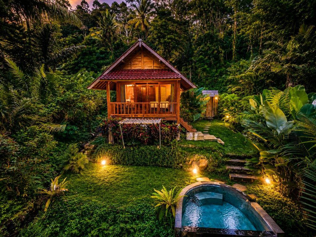a house in the middle of a garden with a pool at The Payung House - Romantic Riverside Villa in Bebandem